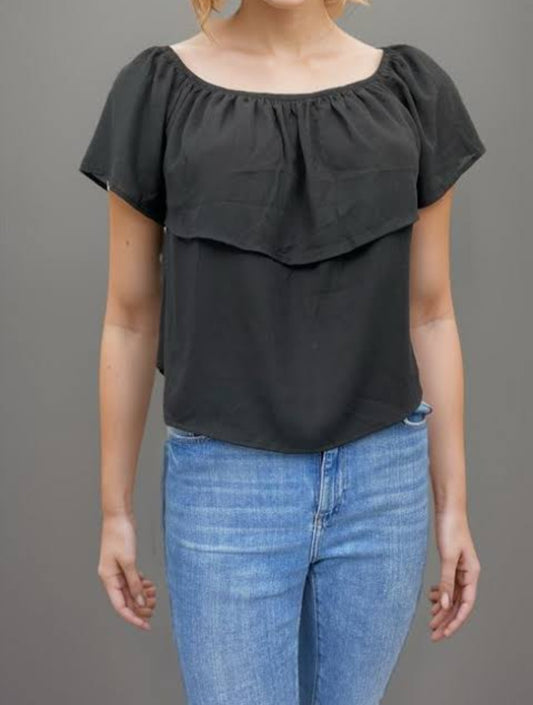 Blusa negra con escote elástico y doble capa frontal.